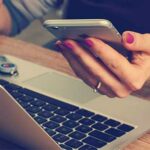 Professionista con smartphone e laptop per gestione digitale documenti fiscali e legali