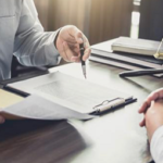 Avvocato sottoscrive documento legale con bilancia della giustizia e libri di diritto sulla scrivania