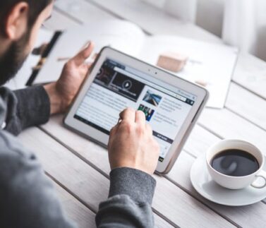 Professionista consulta notizie fiscali su tablet durante pausa caffè in ufficio