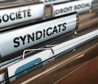 Cartella archivio con etichetta "SYNDICATS" in primo piano, rappresentante documentazione sindacale e diritti dei lavor…