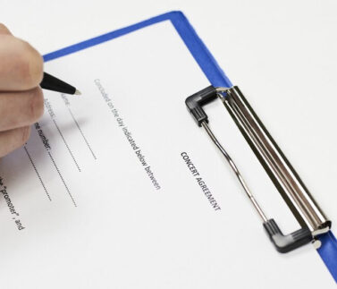 Mano che firma documento legale con penna su clipboard blu