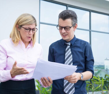 Due professionisti in ufficio moderno consultano documento durante colloquio disciplinare formale