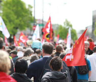 Manifestazione sindacale con bandiere rosse e svizzere, protesta diritti lavoratori e contratti collettivi