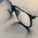 Occhiali su documento legale con logo News Legali USafio, simbolo di consulenza legale e analisi normativa