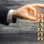 Mano che seleziona figura professionale da torre di persone, mediatore e provvigione