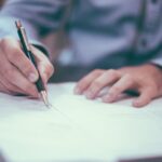 Firma di un documento legale con penna su carta, rappresentando la validità contrattuale e la competenza del foro