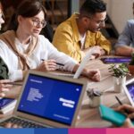 Gruppo di professionisti in riunione collaborativa attorno a tavolo con laptop e documenti di lavoro