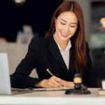 Avvocato donna al lavoro in studio legale con laptop e statuetta della giustizia