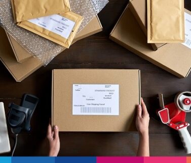 costi-spedizioni-ecommerce Imballaggio e spedizione di pacco con etichetta indirizzo su scrivania logistica ecommerce