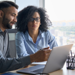 Due professionisti consultano documenti fiscali su laptop in ufficio moderno