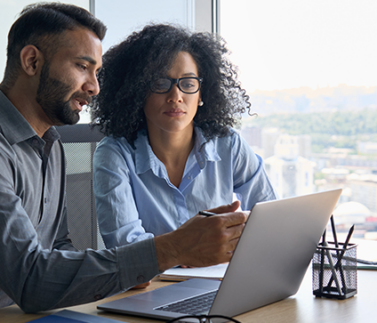 broker-4 Due professionisti consultano documenti fiscali su laptop in ufficio moderno