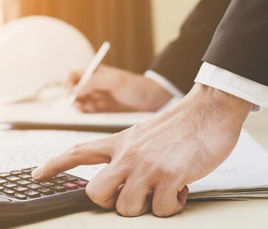 Professionista calcola costi costruzione con calcolatrice e documentazione fiscale