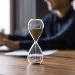 Clessidra su scrivania studio legale, simbolo della gestione del tempo e scadenze professionali