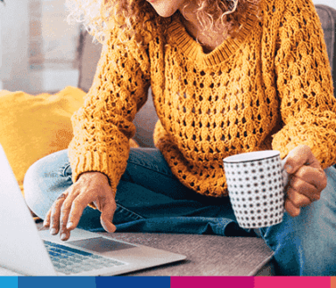 Donna che lavora da casa con laptop e caffè, simboleggia il lavoro ibrido e la flessibilità lavorativa moderna