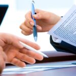 Due professionisti firmano un documento legale con penna blu durante una consultazione fiscale