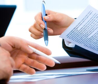 redazione-atti-6 Due professionisti firmano un documento legale con penna blu durante una consultazione fiscale