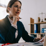 Avvocato donna in studio legale al lavoro su documenti e laptop per redazione atti processuali
