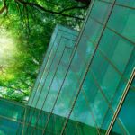 Facciata in vetro verde di studio professionale moderno con alberi sullo sfondo, simbolo di sostenibilità aziendale