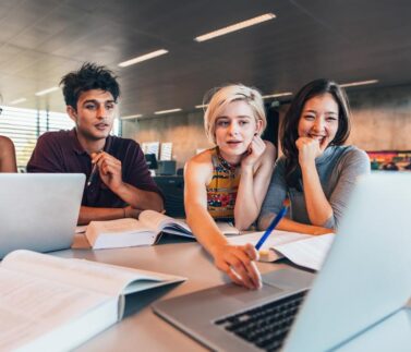 Giovani professionisti in riunione di lavoro collaborativo con laptop e documenti