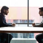 Due professionisti in riunione d'affari discutono questioni legali e contrattuali in ufficio moderno