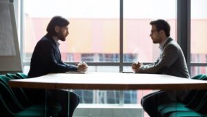 Due professionisti in riunione d'affari discutono questioni legali e contrattuali in ufficio moderno