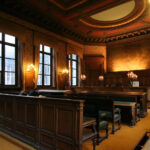 Aula di tribunale italiana con banchi in legno scuro, illuminazione calda e sedili verdi per l'amministrazione della gi…